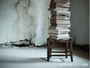 読まずに積み上がった本。冷たい雰囲気の部屋の椅子の上に積み上げられている。読まずに積み上がった悲しい印象。