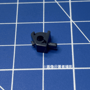 ガンプラのパーツ。跳ね返り実験に用いたピース。素材はPS、小さい方。5角形の形状にはめ込みがあり。濃いグレー
